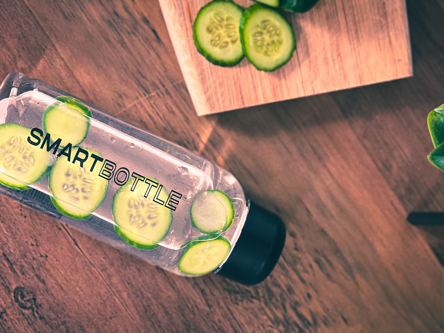 Smartbottle on top of a wooden table with cucumber concoction